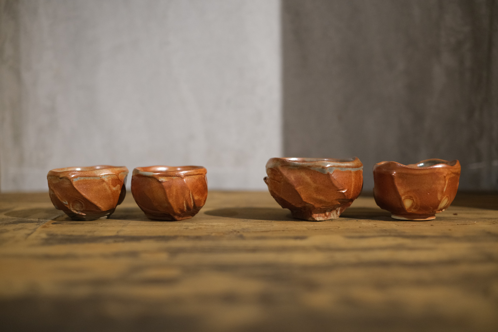 two sets of two cups, one set larger, one smaller. The cups are 
          rounded and come to square, carved feet. The outsides of the cups have twisting carved and thrown edges.