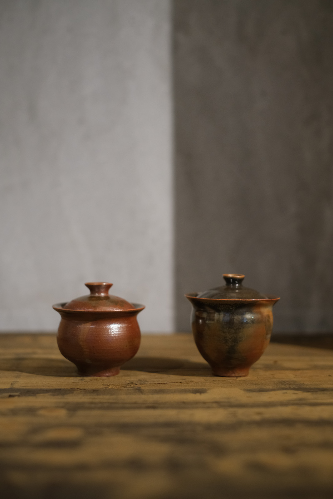 two round bellied gaiwan, one shorter, one taller. The smaller 
          is matte red, the other orang and black and a bit more shiny