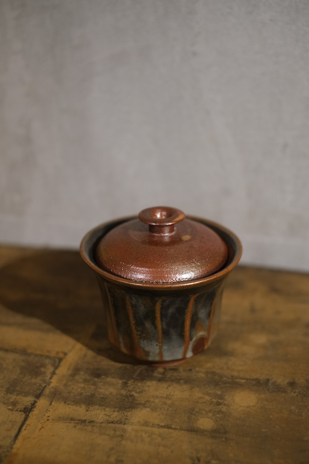 a red and black gaiwan with a circular nob on the lid