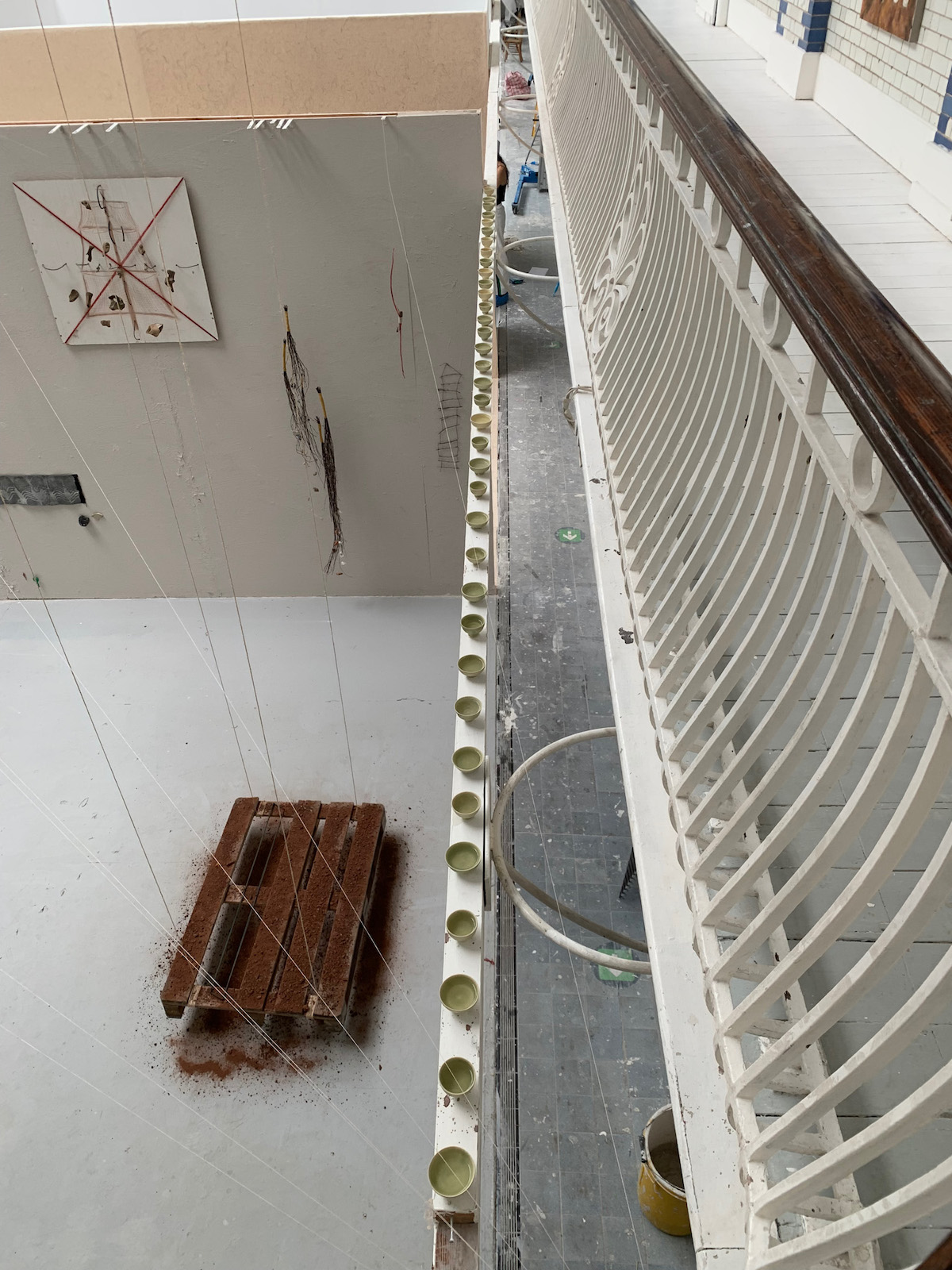 a view from above in which a beam is visible
      where cups holding a small amount of liquid are lined up above the exhibition space