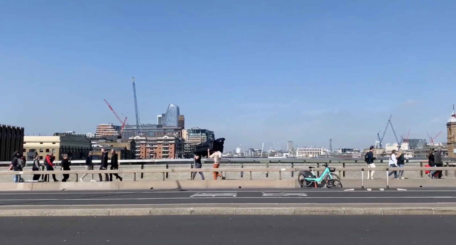 a wide angle shot of two people carying a couch across London Bridge