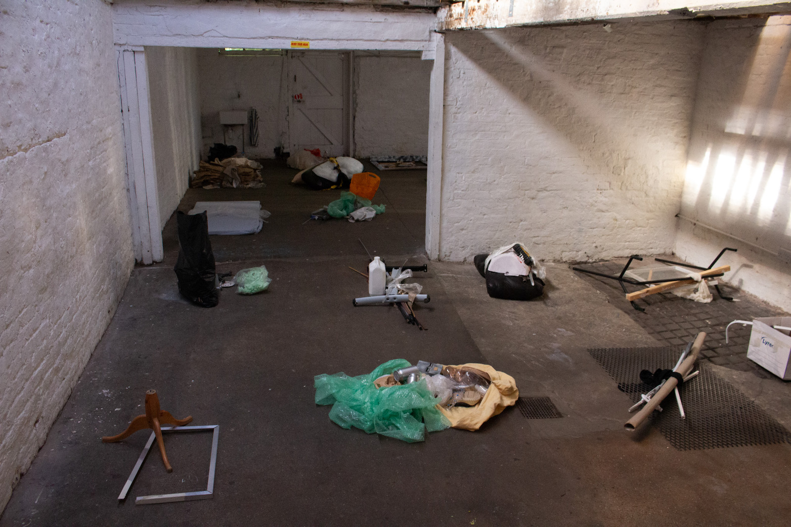 a d-i-y gallery space with bundles of waste items layed out in a grid on the floor