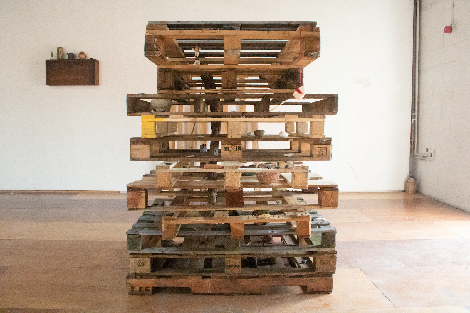 a stack of moving pallets filled with various objects: 
        ceramic shards, bits of chalk and butterfly bush, pots